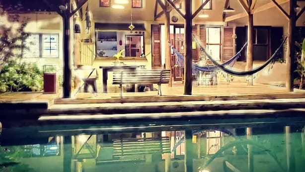 Zona de piscina amb un espai de seients cobert, un hamaca i vistes a la piscina.