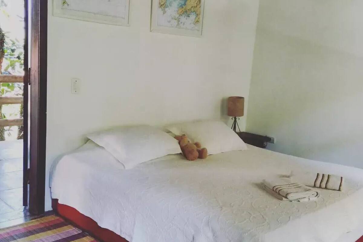 A bedroom with a bed, pillows, a lamp, and a colorful striped rug.