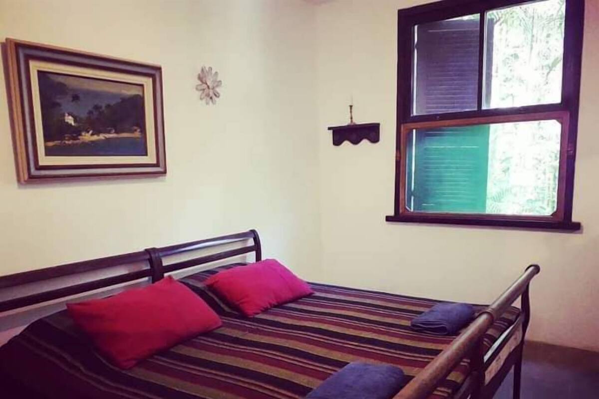 A bed with a striped bedspread, two red pillows, and a wooden headboard.