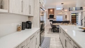 Una cucina moderna con mobili bianchi, un'isola centrale e un'area pranzo con divano.