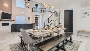Un'elegante zona pranzo con tavolo in vetro apparecchiato per quattro persone, una panca e una scala che conduce a un piano superiore.