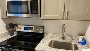 A kitchen with stainless steel appliances, a granite countertop, and a stainless steel sink. - Modernized Studio Apartment in Gadsden, AL (Gadsden)