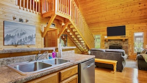 A wooden cabin interior with a kitchen, dining area, and living room. - Great Cabin sleeps 8, New Furnishings, Loft w/ Arcade Games, Hot Tub & Fireplace (Sevierville)