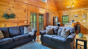 A cozy cabin interior with two leather sofas, a wooden ceiling, and a kitchen area. - Great Cabin sleeps 8, New Furnishings, Loft w/ Arcade Games, Hot Tub & Fireplace (Sevierville)