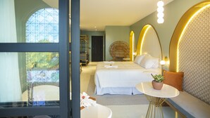 A modern hotel room with a large bed, a round seating area, and a view of the outdoors.