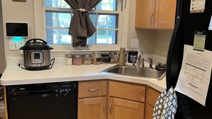 A kitchen with a Bosch dishwasher, a black refrigerator, wooden cabinets, a window with a curtain, and a sink. - Park-like and sports bar - close to MSU (Lansing)