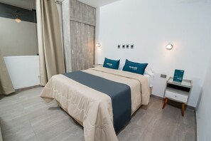 Een moderne hotelkamer met een groot bed, een nachtkastje en een wandlamp.