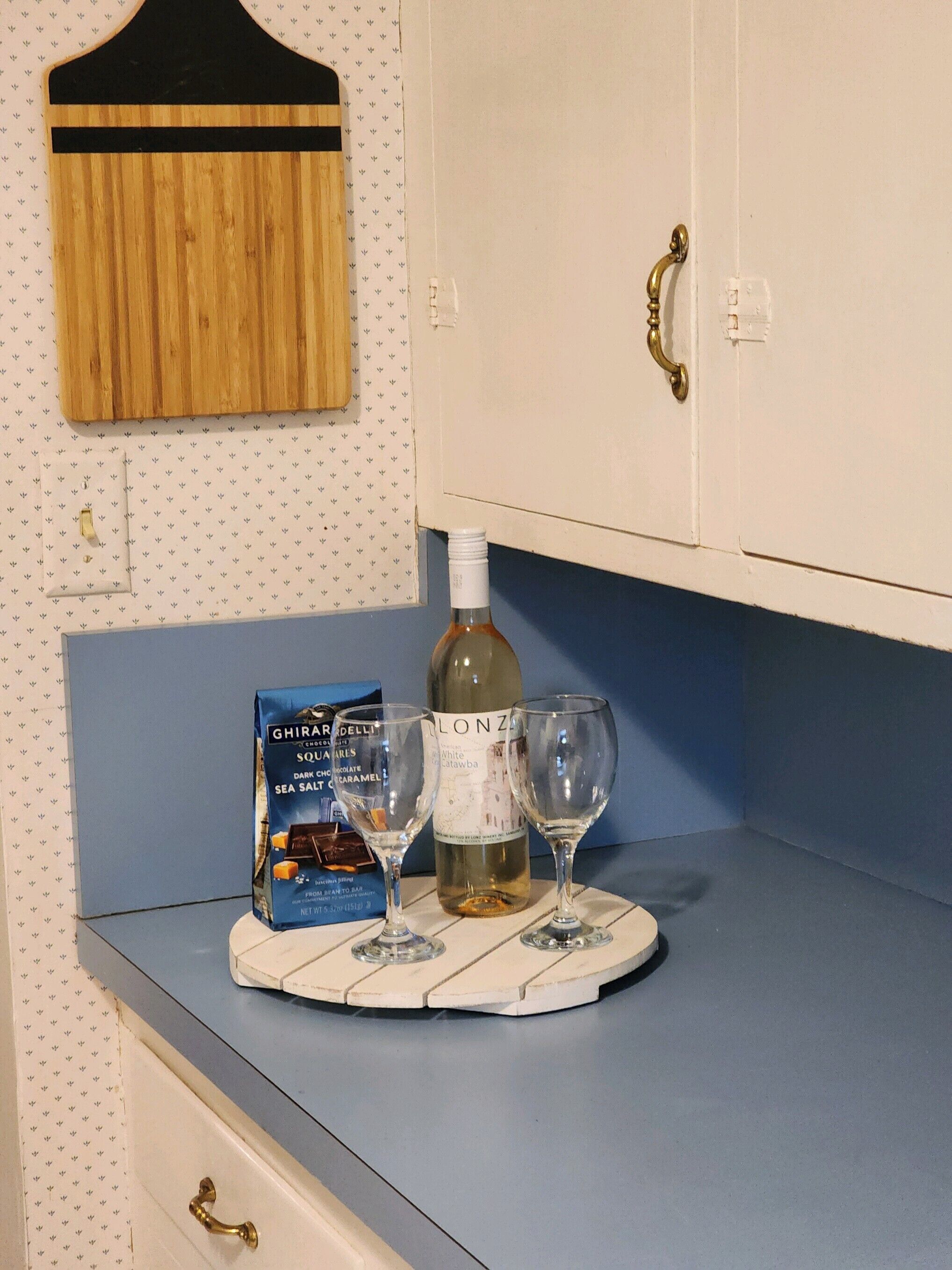 Un comptoir de cuisine avec une bouteille de vin, deux verres à vin et un emballage de tablette de chocolat.