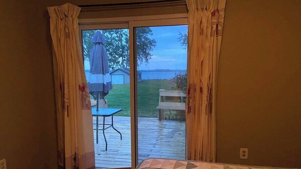 Quarto com uma cama grande, porta de correr de vidro que dá para um pátio externo com mesa e cadeiras.