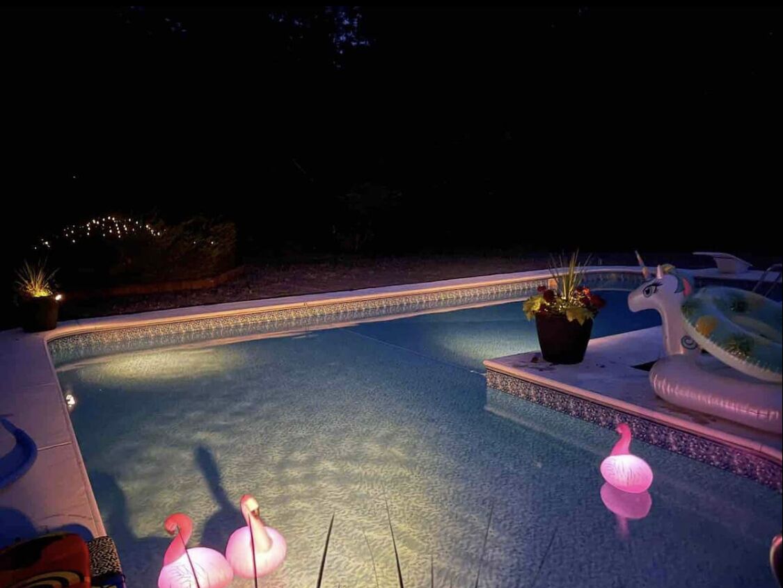 Une piscine avec un bord carrelé, une chaise longue et une plante en pot.