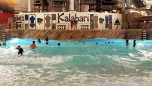 Parque aquático interno com piscina de ondas e uma placa com o texto 'Kalabari'.