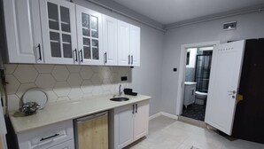 A modern kitchen with white cabinets, a hexagonal tile backsplash, and a built-in dishwasher. - Ortaköy Tiny One (Istanbul)