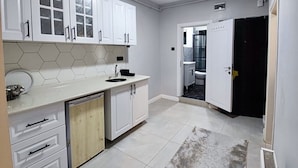 A compact kitchen with white cabinets, a tiled backsplash, a central sink, and a built-in dishwasher. - Ortaköy Tiny One (Istanbul)