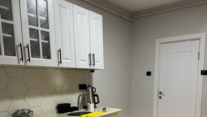 A kitchen with white cabinets, a dishwasher, a coffee maker, and a sink. - Ortaköy Tiny One (Istanbul)