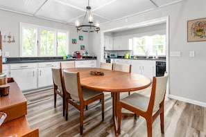 Una cocina moderna con armarios blancos, una mesa de comedor de madera y una lámpara de araña.