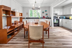 Una cocina amplia con un gran comedor de madera, armarios blancos y vistas al exterior.