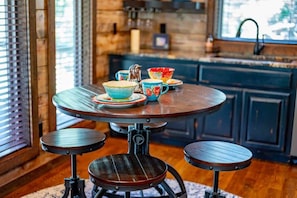 A round dining table with stools, surrounded by colorful bowls and a decorative horse figurine.
