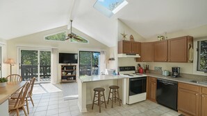 A spacious kitchen with a central island, wooden cabinets, and a large window. - Chappy - Family Beach House (Edgartown)