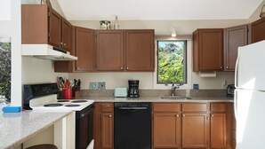 A modern kitchen with wooden cabinets, a dishwasher, a stove, and a coffee maker. - Chappy - Family Beach House (Edgartown)
