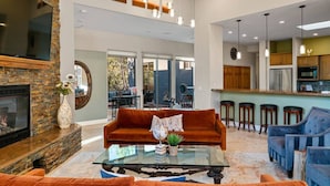 A spacious living area with a fireplace, a glass coffee table, and a comfortable seating arrangement. - 206A&B Lake Dr Entire Home · Luxury Home; Spa, Fireplaces, Gourmet Kitchen (Sedona)