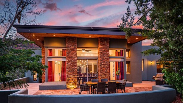 A modern house with a patio, stone columns, and a dining area. - 206A&B Lake Dr Entire Home · Luxury Home; Spa, Fireplaces, Gourmet Kitchen (Sedona)