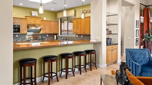 A kitchen with wooden cabinets, a granite countertop, and a bar area with stools. - 206A&B Lake Dr Entire Home · Luxury Home; Spa, Fireplaces, Gourmet Kitchen (Sedona)