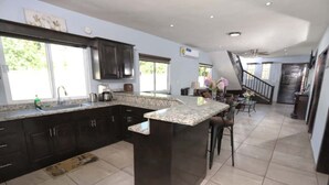 A spacious kitchen with dark cabinets, a granite countertop island, and a large window providing natural light. - Relaxing Getaway w/ Pool, Billiards, Steps to the Beach – Perfect for Families! (Puerto Peñasco)