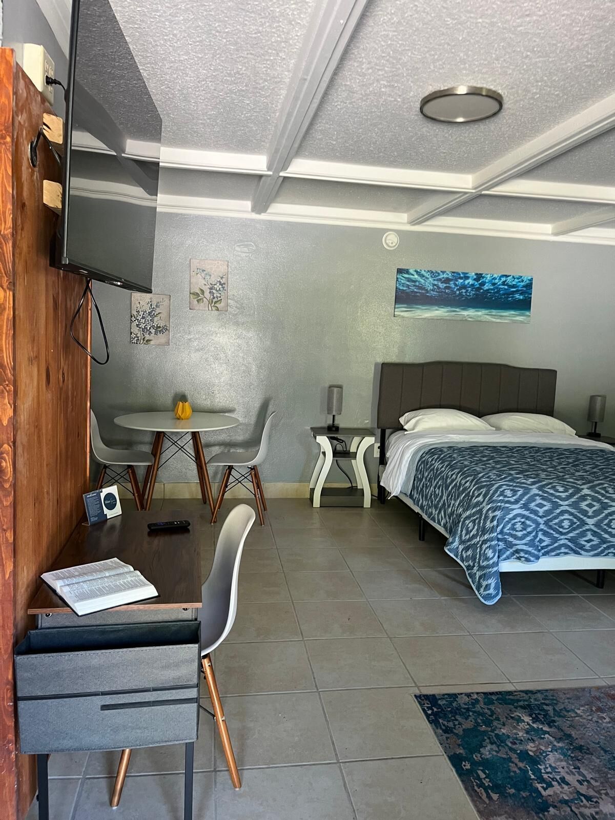 Een hotelkamer met een bed, een bureau met stoel, een kleine tafel met twee stoelen, een aan de muur bevestigde televisie en kunst aan de wanden.