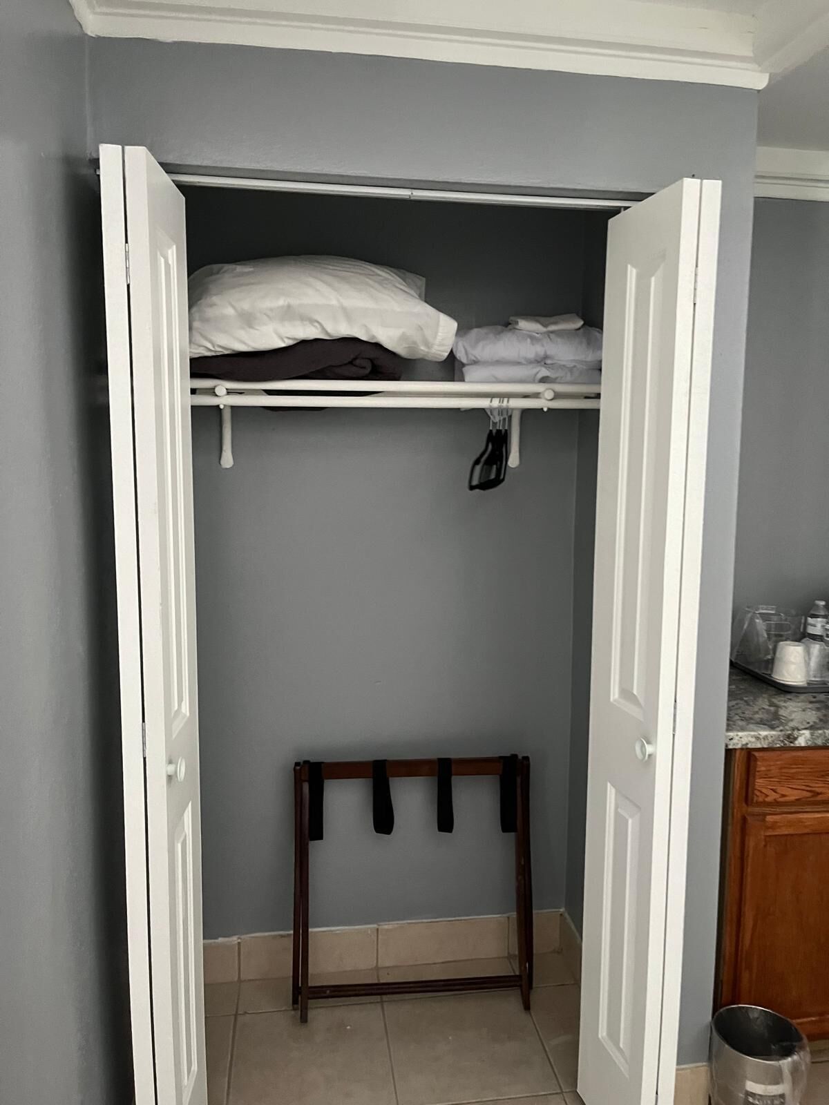 A small, enclosed closet with a bed frame, a hanging rack, and a small table.
