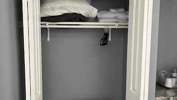 A small, enclosed closet with a bed frame, a hanging rack, and a small table.