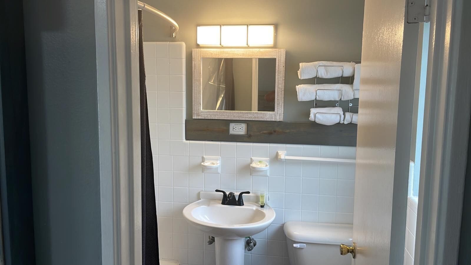 A bathroom with a white sink, a mirror, a towel rack, and a toilet.