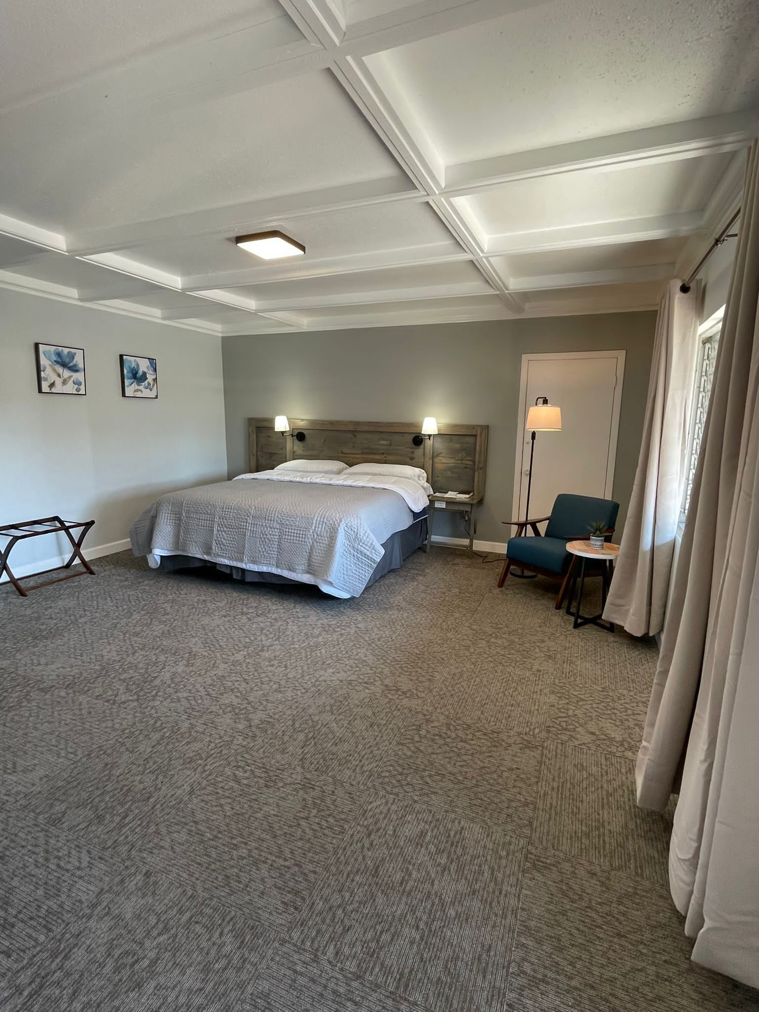 Una habitación de hotel con una cama grande, un escritorio, una silla y una mesita de noche.