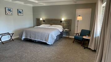 A hotel room with a large bed, a desk, a chair, and a nightstand.