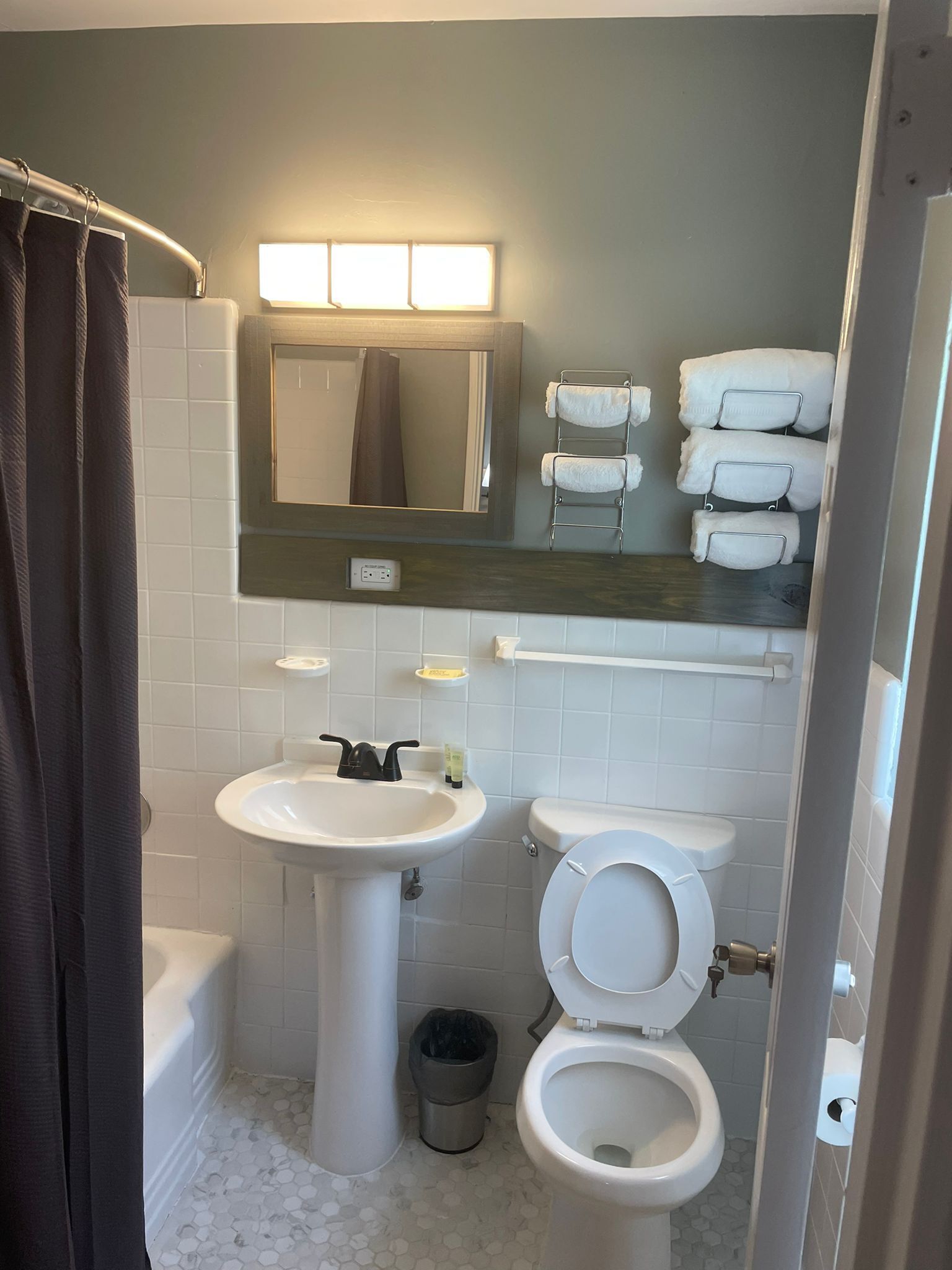 A bathroom with a sink, toilet, and a mirror above the sink. There are towels hanging on a rack and a shower curtain.