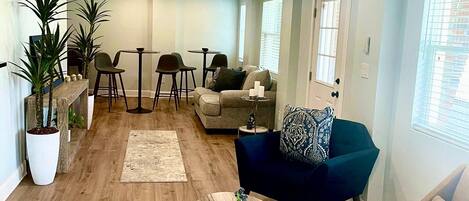A spacious living area with a wooden floor, a blue sofa, a round coffee table, and a ceiling fan.