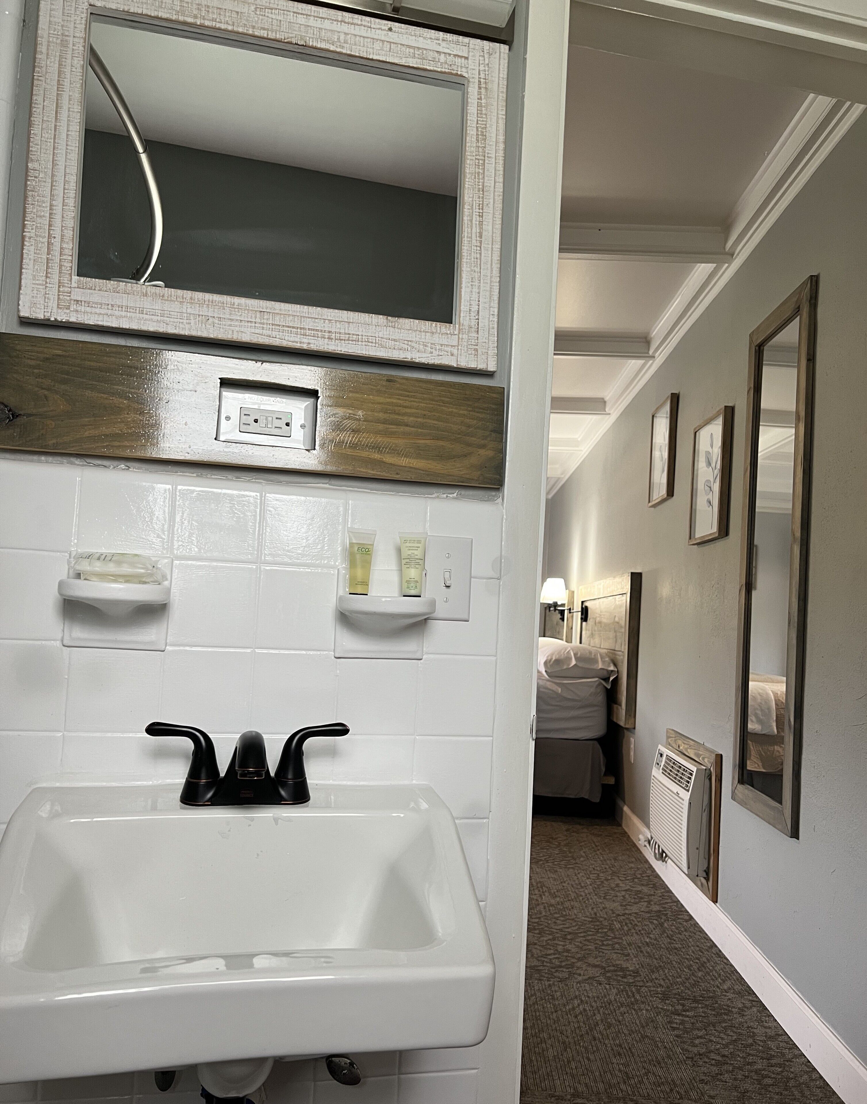 A bathroom with a white sink, a mirror, and a shower area. There are toiletries on the wall and a towel rack.