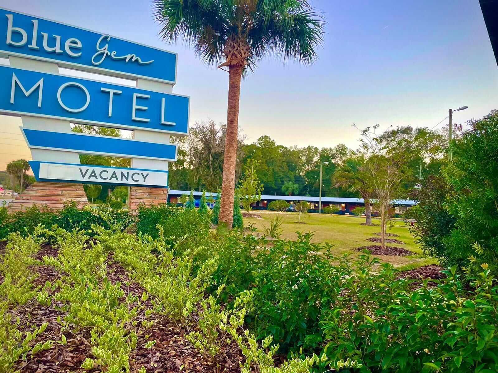 A motel sign with 'Blue Gem Motel' and 'VACANCY' visible.