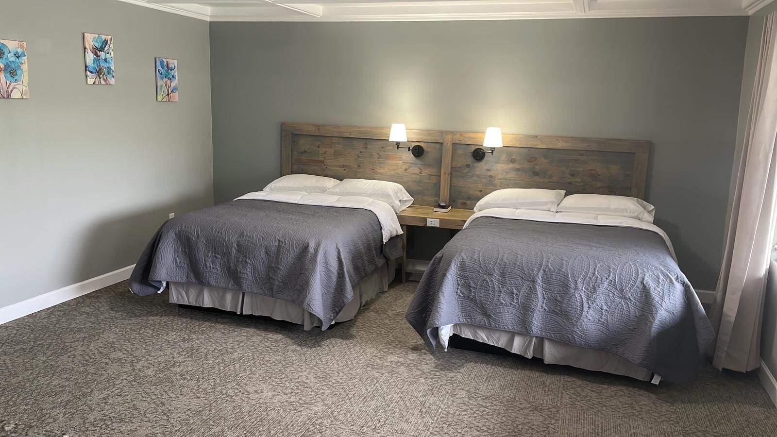 A hotel room with two single beds, a wooden headboard, a nightstand, and a carpeted floor.