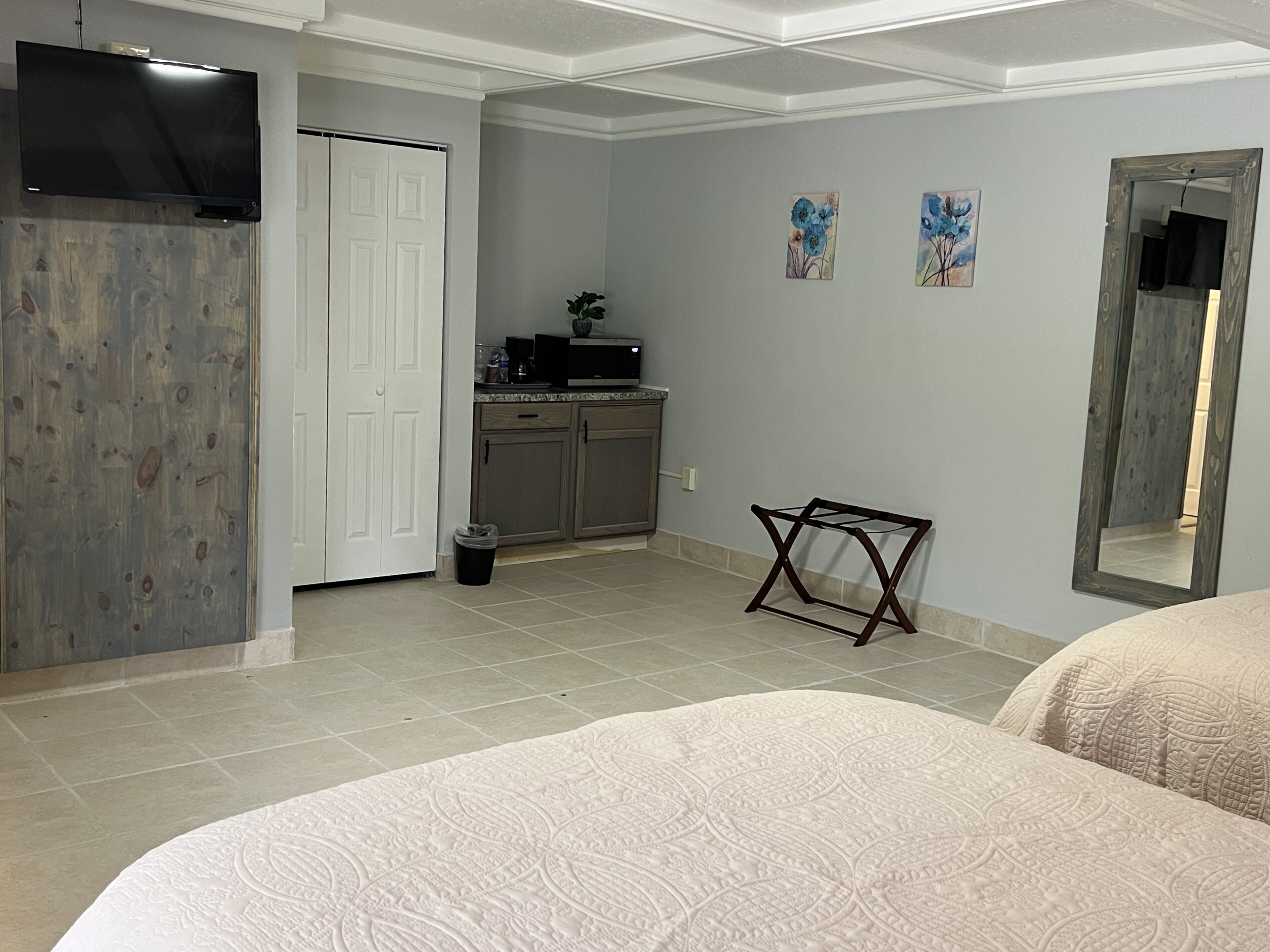 Un dormitorio con dos camas, televisor, armario y una pequeña kitchenette.