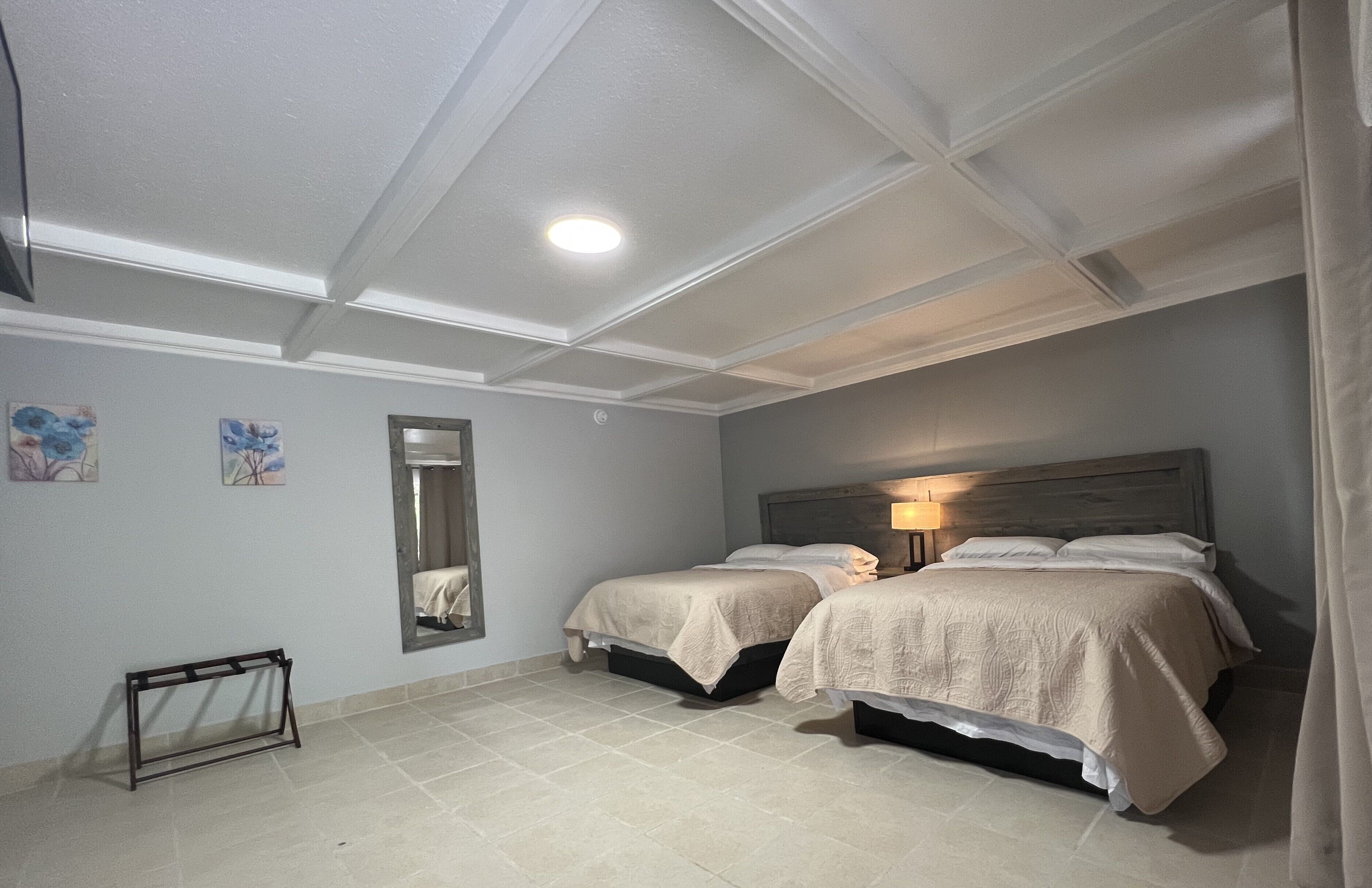 A bedroom with two beds, a mirror, and a bedside table.