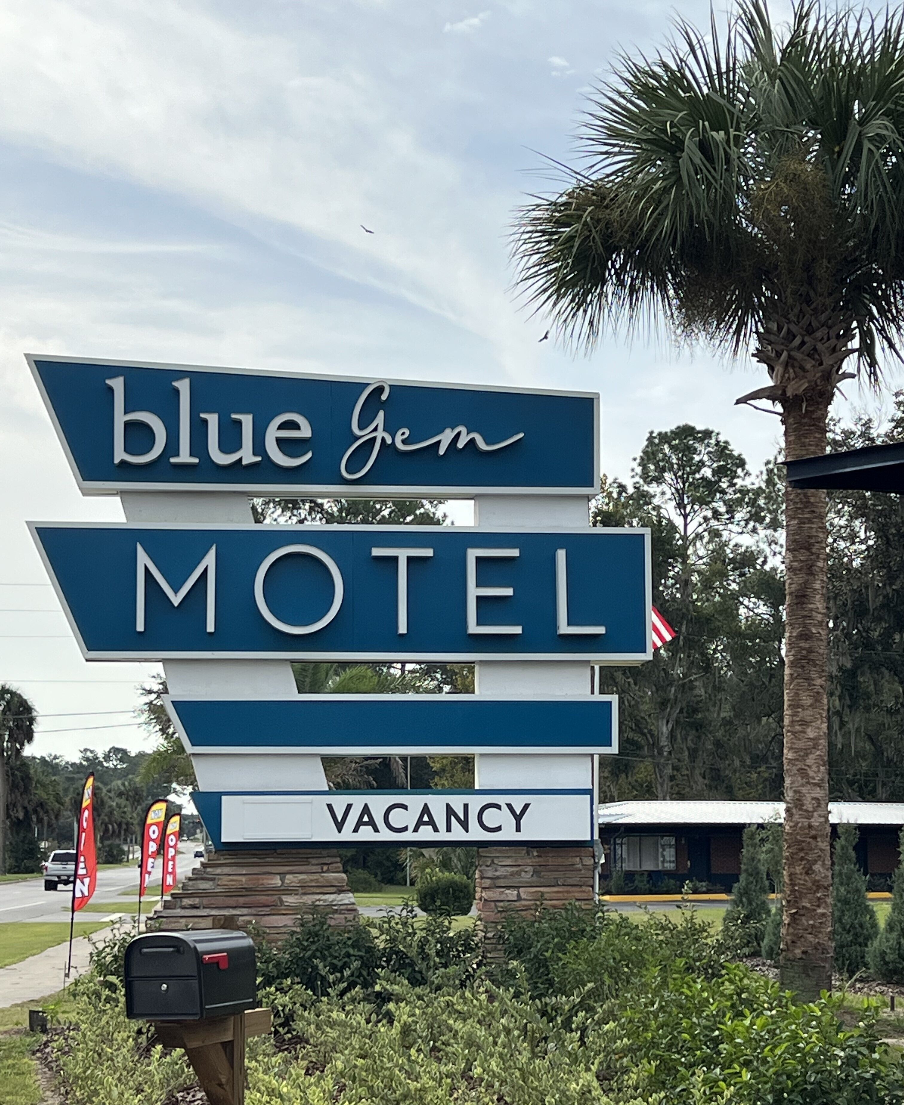 A motel sign with 'blue gem' and 'VACANCY' displayed prominently.