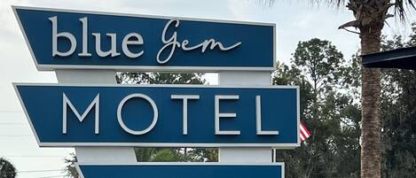A motel sign with 'blue gem' and 'VACANCY' displayed prominently.