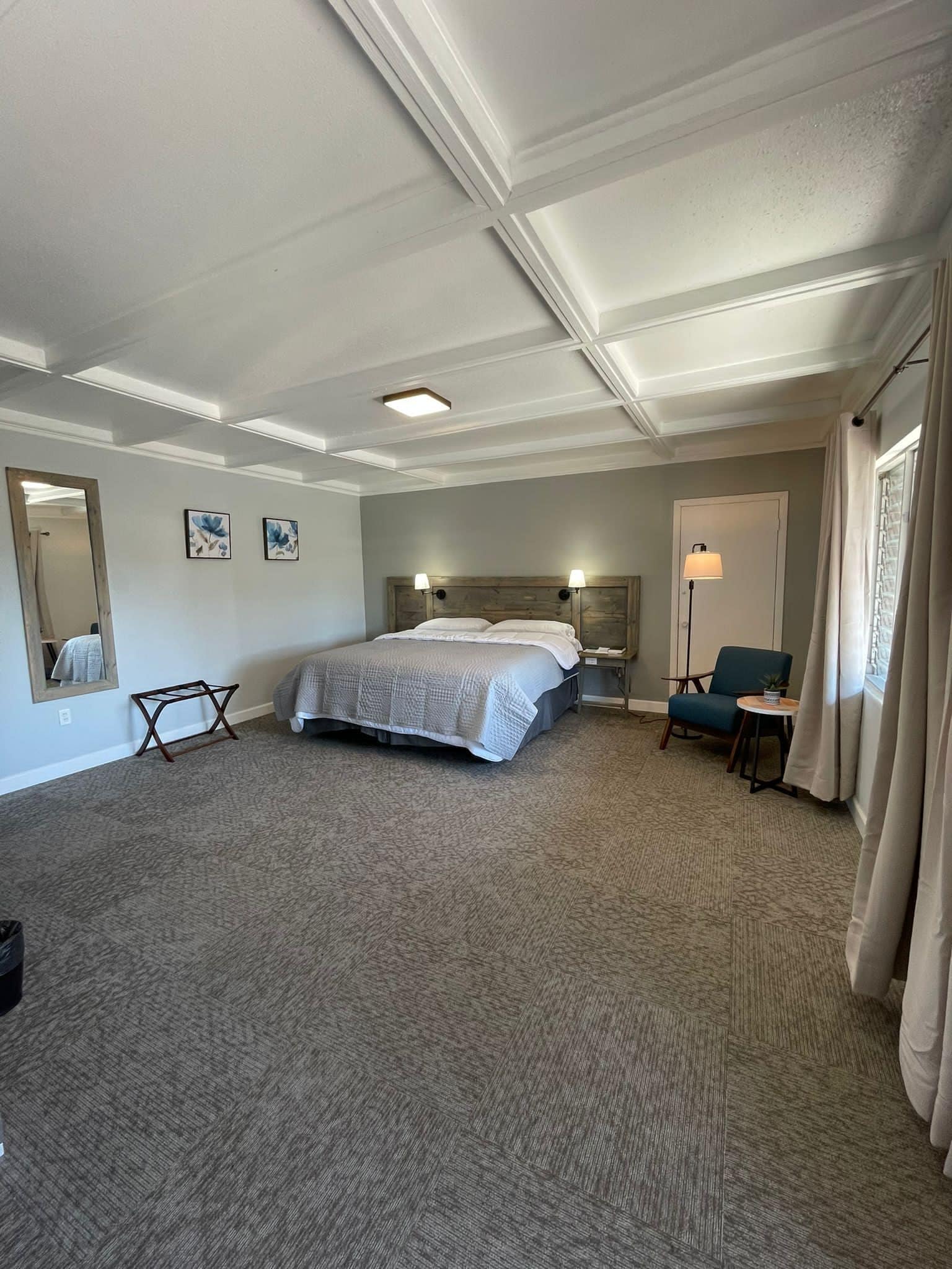 Een hotelkamer met een groot bed, een bureau, een stoel, een kleine tafel en een spiegel.