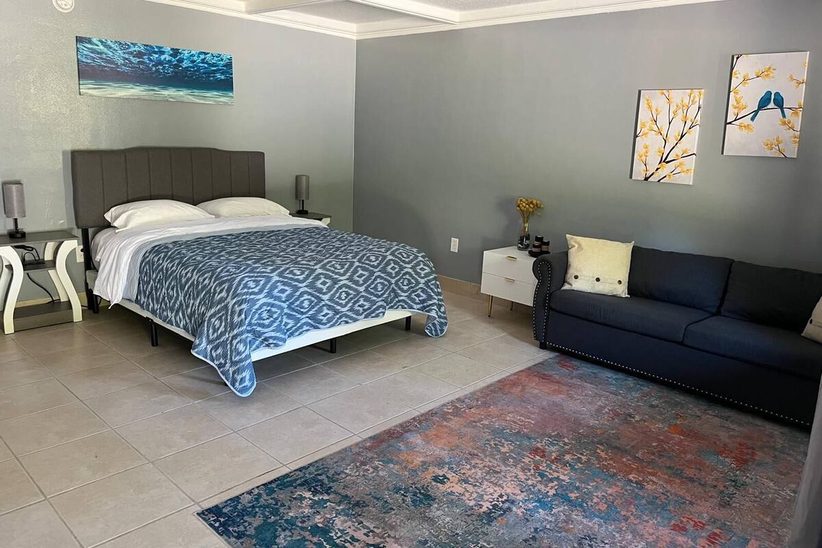 A modern bedroom with a bed, a sofa, and artwork on the walls.