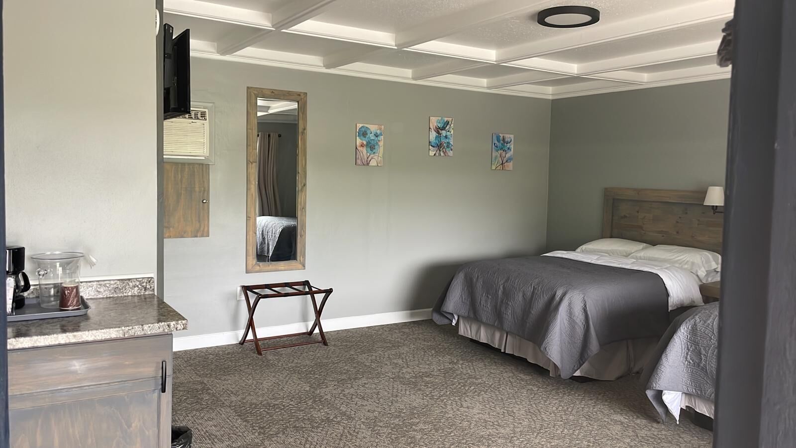 Une chambre à coucher comprenant un lit, une table de chevet, un miroir et une petite table sur laquelle se trouve une machine à café.