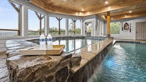 Une grande piscine intérieure dotée d’un plafond en bois et de grandes fenêtres.