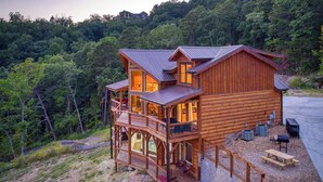 Une cabane en bois dotée d’un balcon, d’un espace extérieur aménagé pour s’asseoir et offrant une vue sur la forêt environnante.