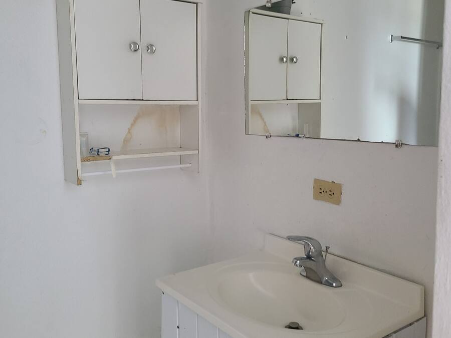 A bathroom with a white sink, a mirror, and a cabinet with a shelf.