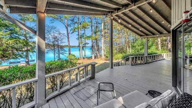 A covered outdoor deck with a view of the ocean and trees. - Your Private Lakefront Retreat (Nacogdoches)