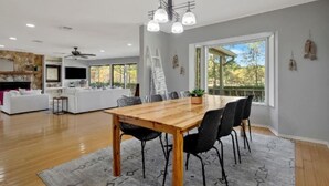 A spacious living area with a wooden dining table, black chairs, and a gray rug. - Your Private Lakefront Retreat (Nacogdoches)